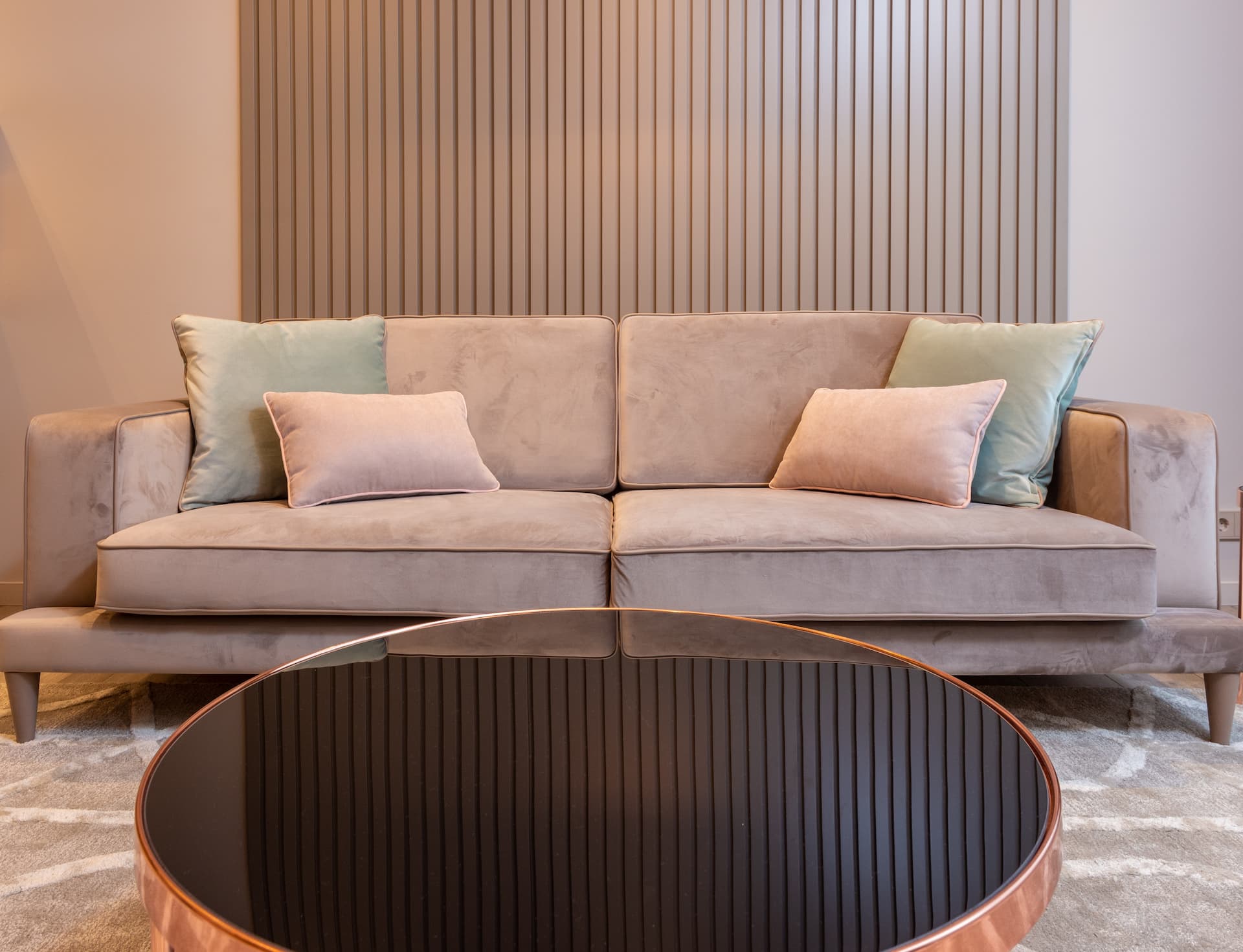 Sofá color rosa y mesa con cristal negro como muebles de salón